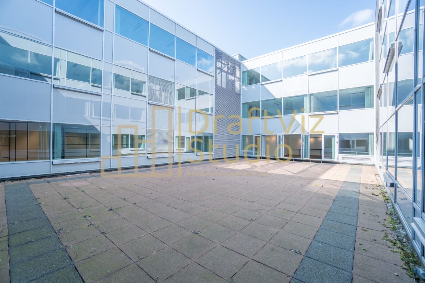 Courtyard-Original Image Modern courtyard with glass buildings and a stone pavement under a clear blue sky.